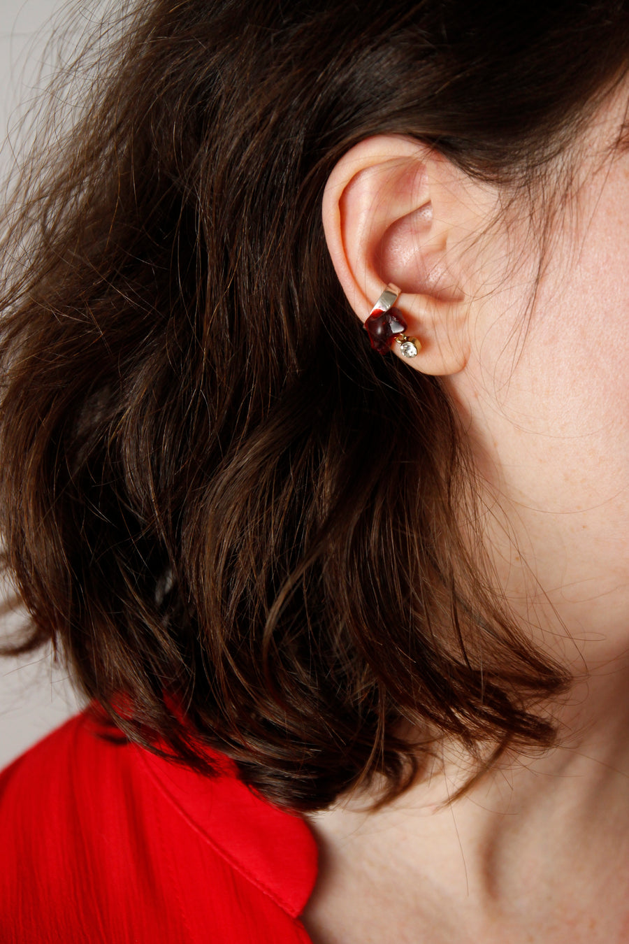 Woman wearing a One-of-a-Kind Handcrafted Dangling Ear Cuff by Gré with red Agate and sterling silver chain